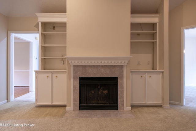 unfurnished living room featuring baseboards, light colored carpet, and a tiled fireplace
