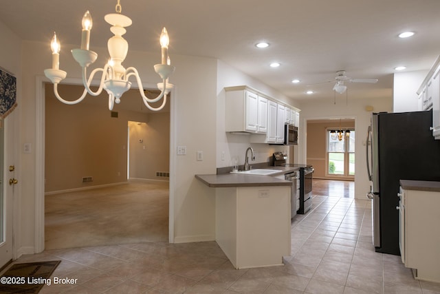 kitchen featuring dark countertops, a sink, ceiling fan with notable chandelier, light carpet, and stainless steel appliances