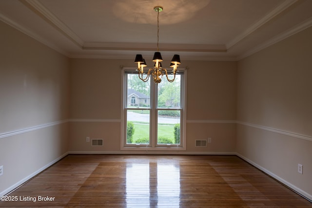 unfurnished room with visible vents, a tray ceiling, hardwood / wood-style floors, and a chandelier