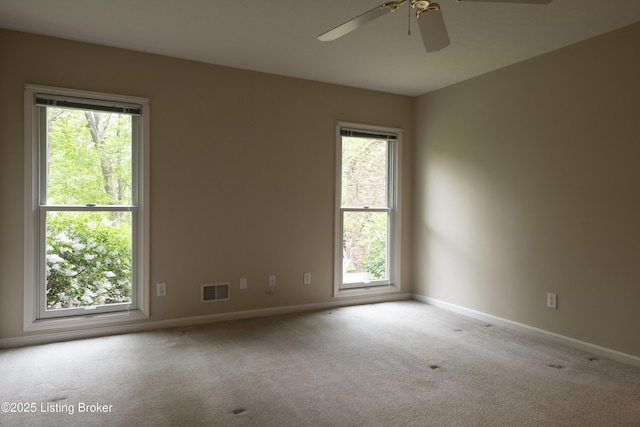 carpeted empty room featuring baseboards, ceiling fan, and visible vents