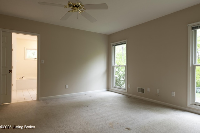 carpeted spare room featuring a ceiling fan, baseboards, and visible vents