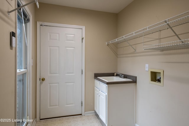 laundry room with cabinet space, baseboards, a sink, and hookup for a washing machine