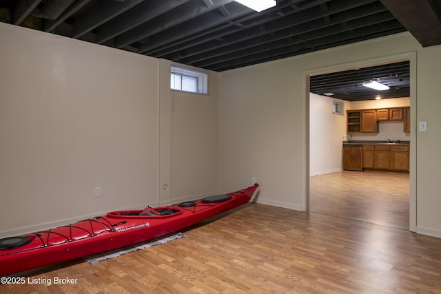 exercise room with a sink, baseboards, and light wood-style flooring