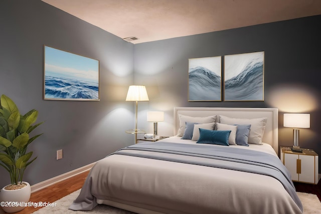 bedroom featuring baseboards, visible vents, and wood finished floors
