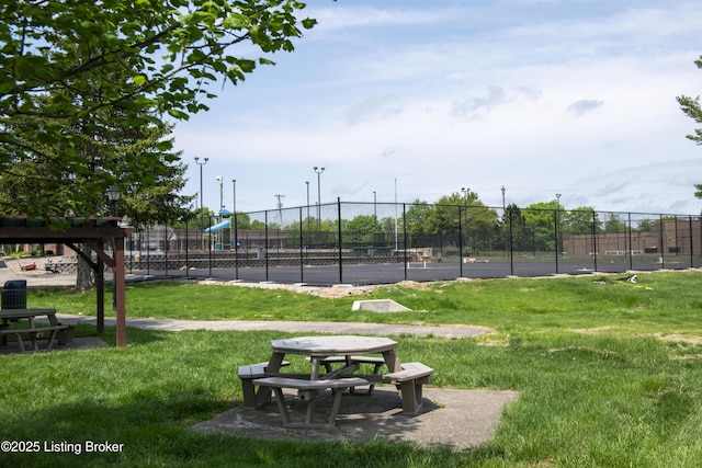 view of property's community with fence, a yard, and playground community