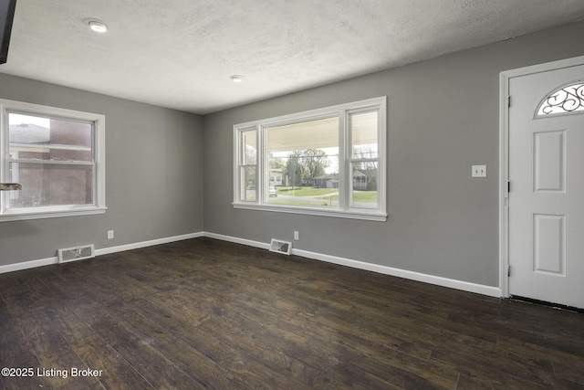 foyer featuring visible vents, a textured ceiling, dark wood finished floors, and baseboards