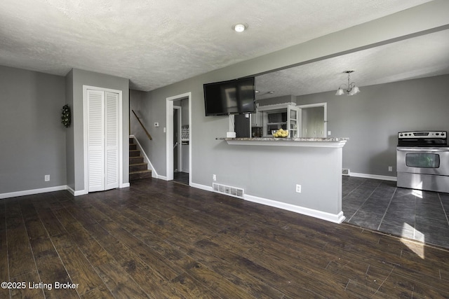 unfurnished living room featuring an inviting chandelier, stairs, baseboards, dark wood-type flooring, and visible vents