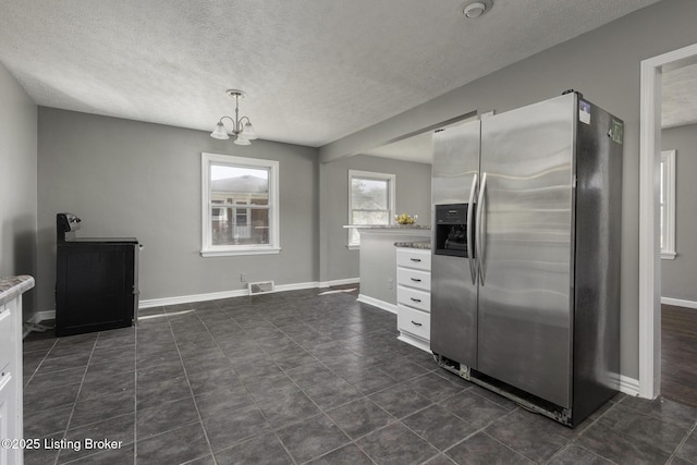 kitchen featuring an inviting chandelier, a textured ceiling, white cabinetry, stainless steel refrigerator with ice dispenser, and visible vents