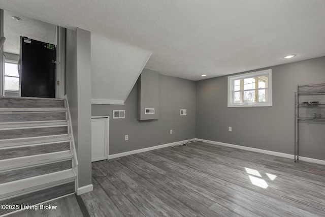 below grade area featuring visible vents, stairs, baseboards, and wood finished floors