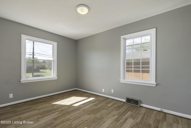 empty room with visible vents, baseboards, and wood finished floors