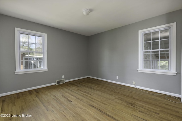 unfurnished room with baseboards, wood finished floors, and visible vents