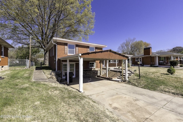 exterior space featuring a lawn, fence, an attached carport, and brick siding