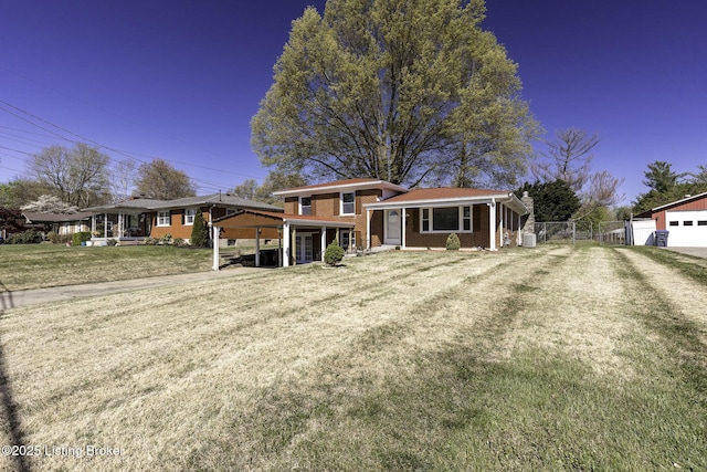 tri-level home with brick siding, fence, and a front yard