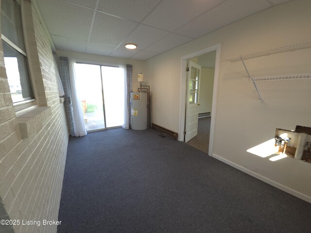 empty room with baseboards, water heater, a drop ceiling, and carpet floors