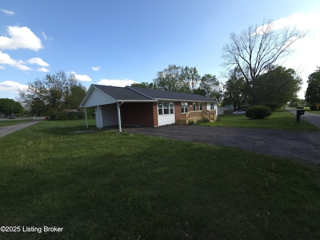view of front facade featuring a carport, a deck, a front lawn, and aphalt driveway
