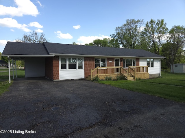 ranch-style house featuring crawl space, driveway, a carport, brick siding, and a front lawn