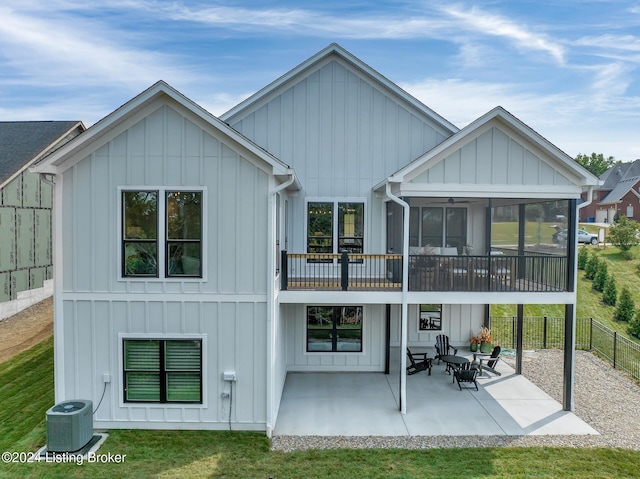 back of house featuring board and batten siding, central AC unit, a sunroom, a fenced backyard, and a patio