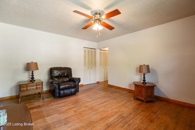 sitting room featuring baseboards, a ceiling fan, and light wood-type flooring