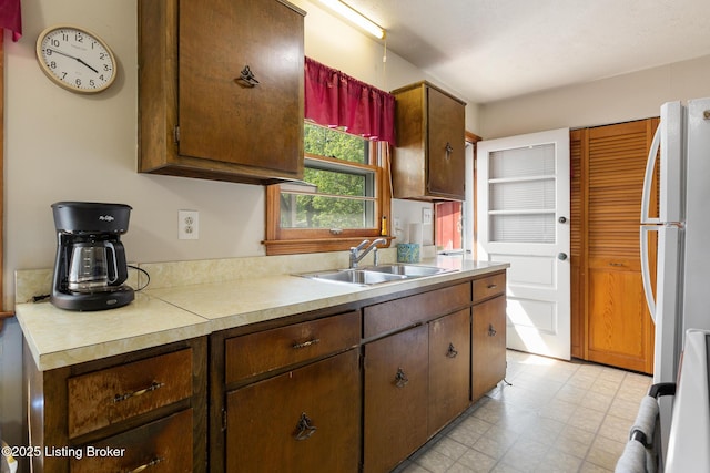 kitchen with freestanding refrigerator, a sink, and light countertops