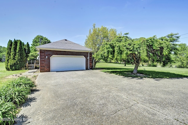view of side of home featuring a yard, brick siding, an attached garage, and concrete driveway