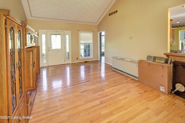 foyer featuring visible vents, light wood finished floors, baseboards, and high vaulted ceiling
