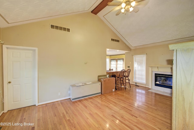 living area with wood-type flooring, a ceiling fan, high vaulted ceiling, and visible vents