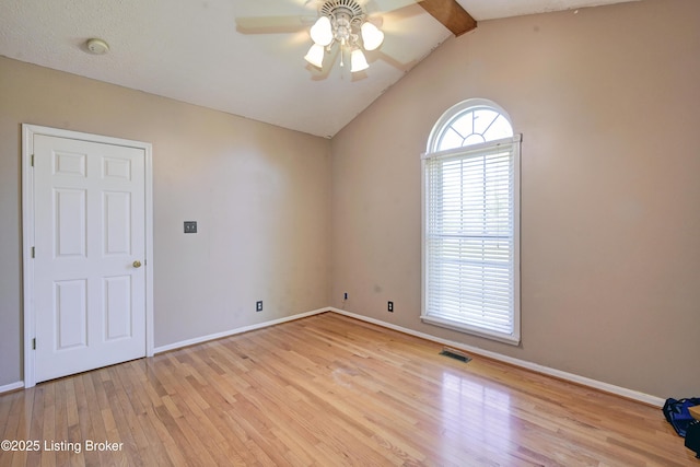 spare room with ceiling fan, lofted ceiling with beams, baseboards, wood finished floors, and visible vents