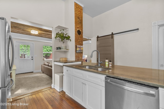 612 E Ormsby Ave, Louisville, KY 40203 - kitchen with appliances with stainless steel finishes, a sink, a barn door, white cabinetry, and hardwood / wood-style flooring