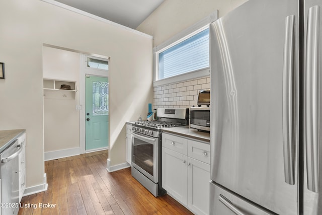 612 E Ormsby Ave, Louisville, KY 40203 - kitchen with stainless steel appliances, backsplash, white cabinets, light wood-type flooring, and baseboards