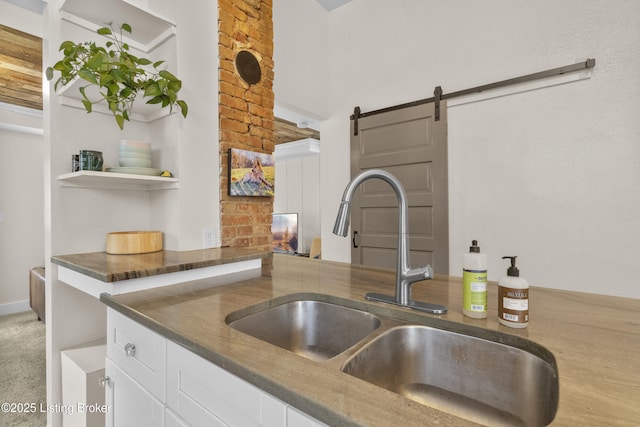 612 E Ormsby Ave, Louisville, KY 40203 - kitchen featuring a sink, a barn door, white cabinets, and dark stone counters