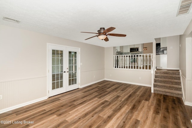 unfurnished living room with a ceiling fan, french doors, wood finished floors, and visible vents
