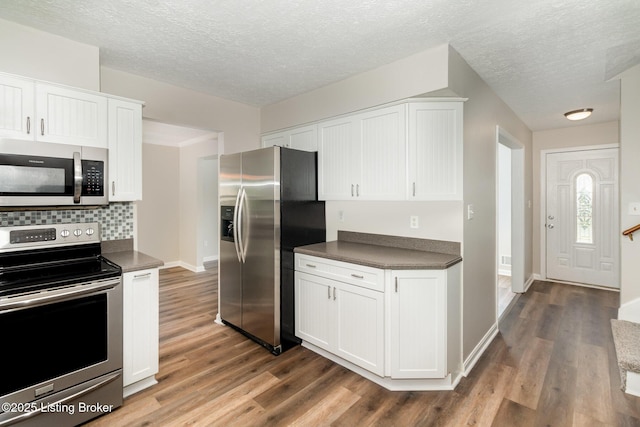 kitchen featuring wood finished floors, dark countertops, and stainless steel appliances