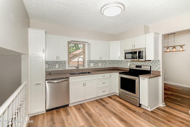 kitchen with a sink, light wood-style flooring, appliances with stainless steel finishes, and backsplash