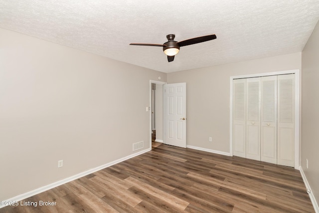 unfurnished bedroom featuring a textured ceiling, baseboards, wood finished floors, and visible vents