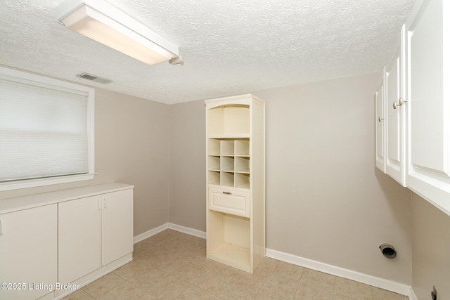 unfurnished bedroom featuring baseboards, a textured ceiling, light tile patterned flooring, and visible vents
