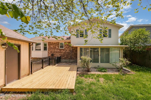 back of house with fence, brick siding, a wooden deck, a sunroom, and a yard