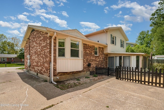 view of side of home featuring fence, a sunroom, crawl space, and brick siding