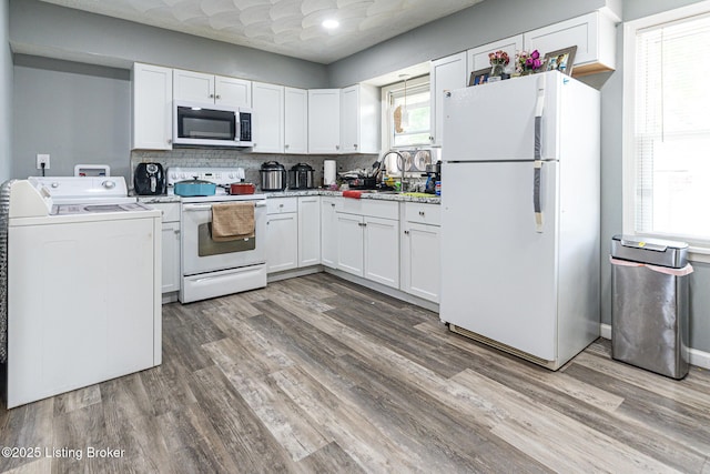 kitchen featuring washer / dryer, white appliances, a sink, and wood finished floors