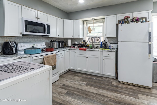 kitchen with a sink, white cabinets, backsplash, and white appliances