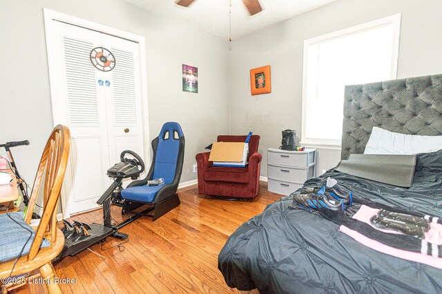 bedroom with ceiling fan, wood finished floors, and a closet