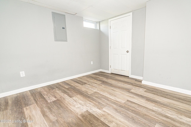 basement featuring baseboards, wood finished floors, and electric panel