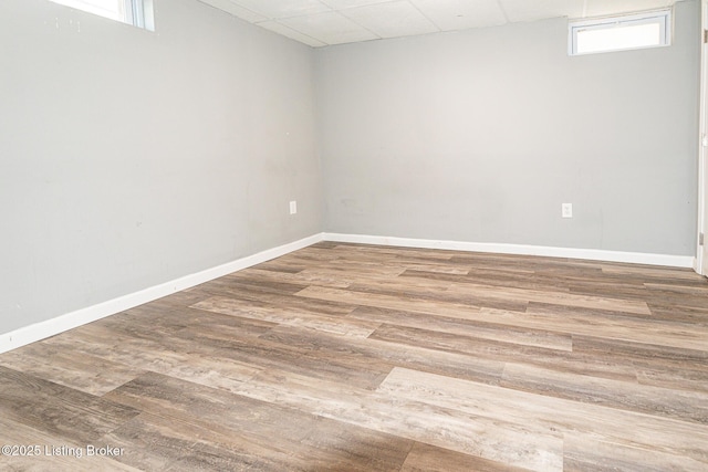 interior space featuring baseboards, a drop ceiling, and wood finished floors