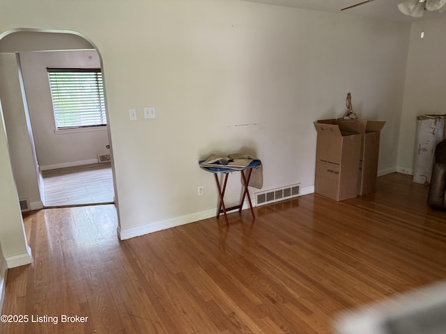 interior space with baseboards, ceiling fan, visible vents, and wood finished floors