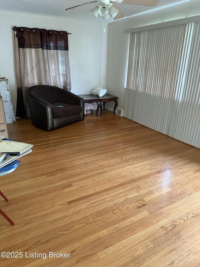 living room featuring a ceiling fan, visible vents, and light wood-style floors