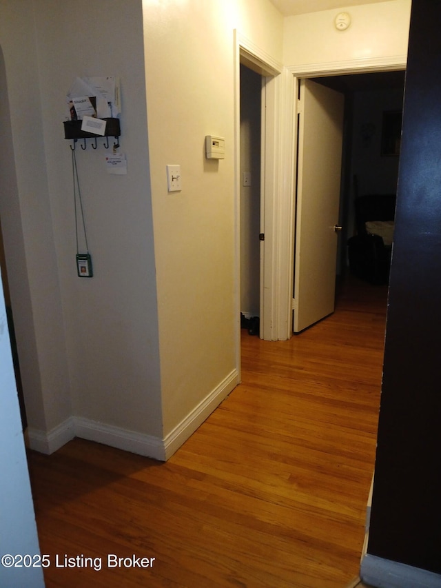 corridor featuring baseboards and light wood-style flooring