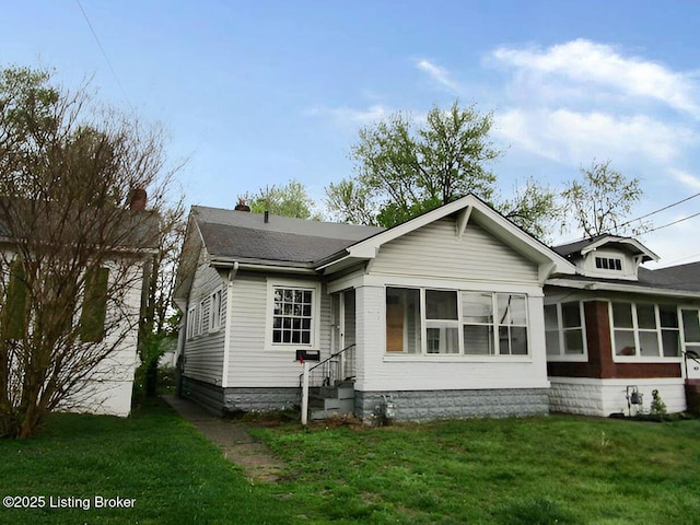 view of front of property featuring a front lawn, roof with shingles, and entry steps
