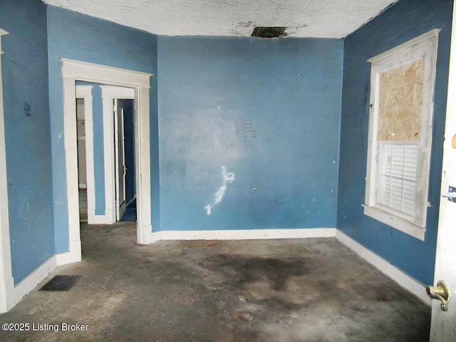 empty room with baseboards, concrete flooring, and visible vents