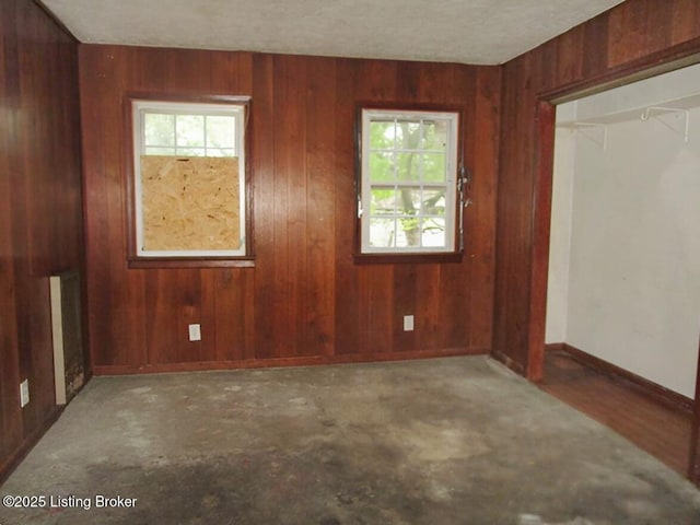 empty room featuring wooden walls and plenty of natural light
