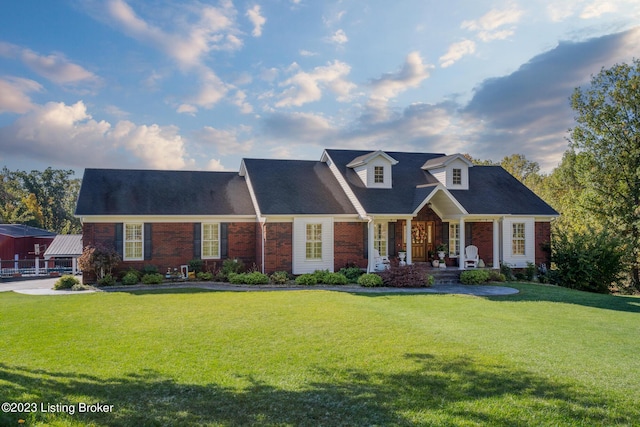 view of front of house with a porch, a front lawn, and brick siding