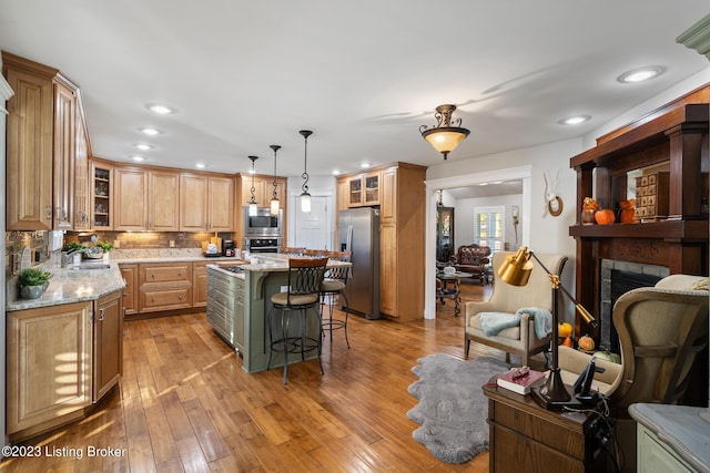 kitchen with appliances with stainless steel finishes, a breakfast bar, a sink, open floor plan, and a kitchen island